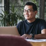 A man works on financial planning on his laptop at his dining room table.
