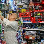 Man stacks shelves in a toy shop.