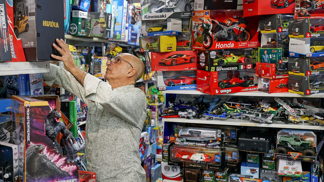 Man stacks shelves in a toy shop.